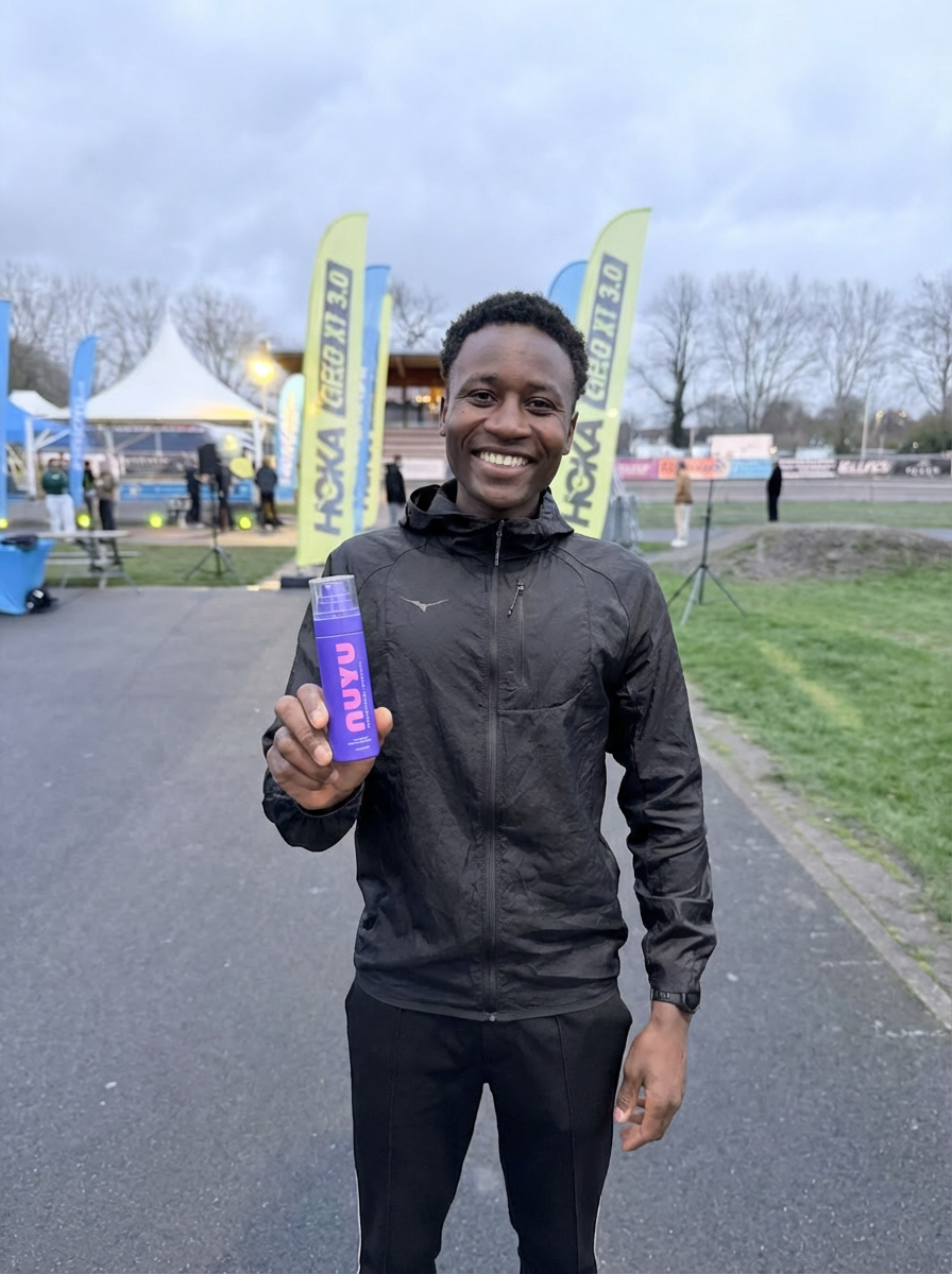 HOKA and NUYU marathon runner holding a purple water bottle with event banners in the background
