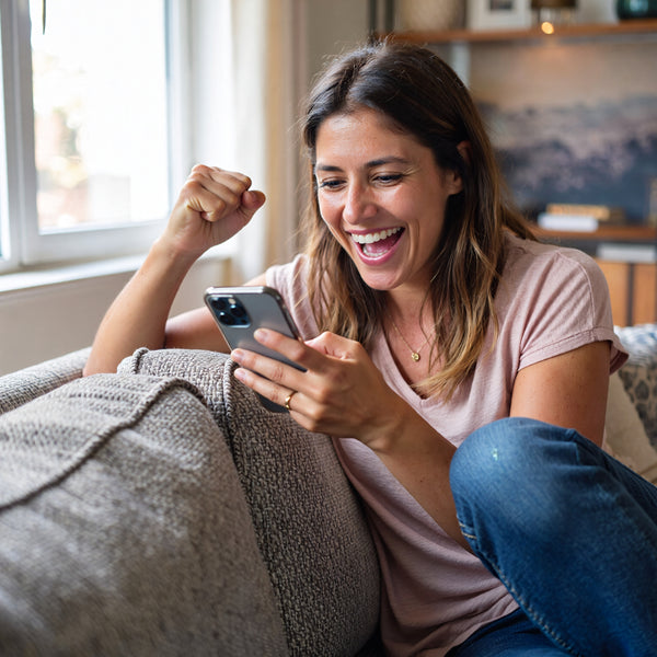 Woman celebrating on phone after receiving NUYU magnesium spray UK wellness delivery
