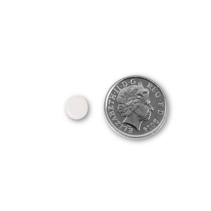NUYU biotin supplement UK tablet size comparison with British coin showing small white capsule