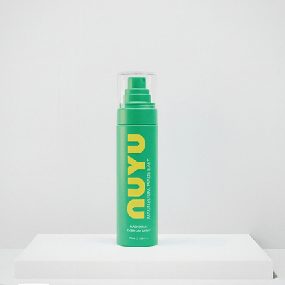 NUYU everyday magnesium spray in green bottle with pump dispenser on white surface