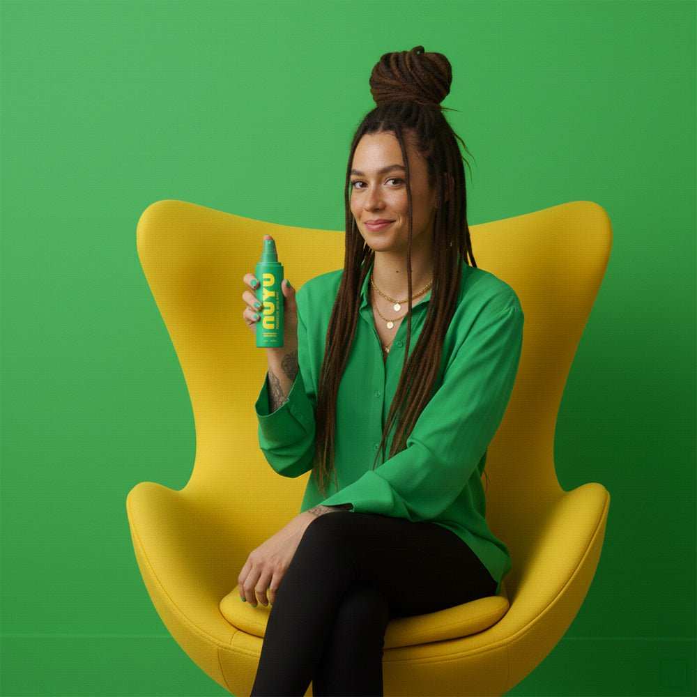 woman sitting on yellow chair holding NUYU Everyday Magnesium Spray bottle for magnesium boost
