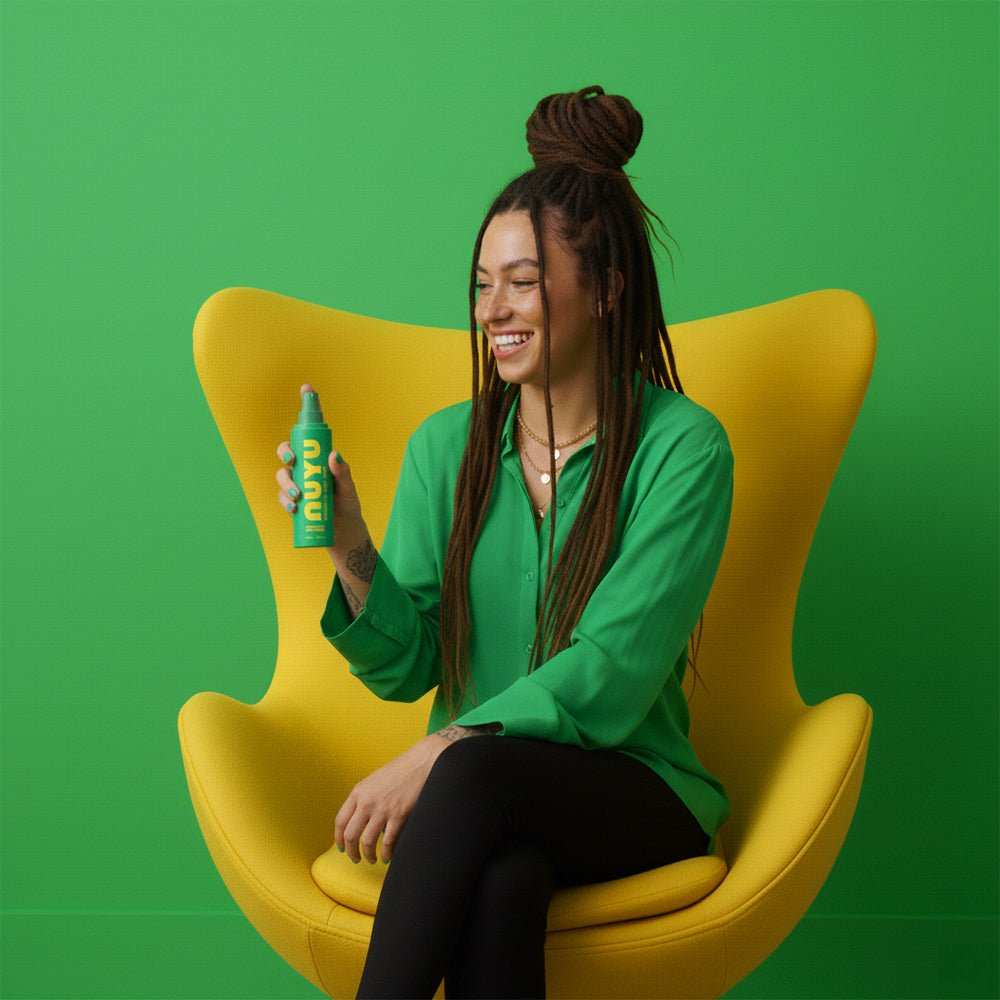 woman holding Everyday Magnesium Spray NUYU bottle for daily magnesium boost sitting on yellow chair