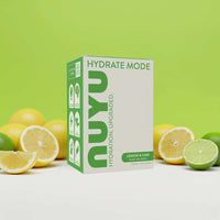 Hydrate Mode lemon and lime electrolyte powder box with fresh citrus fruits on green background