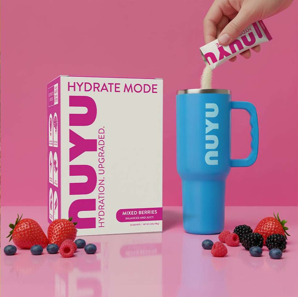 Hydrate Mode Mixed Berry electrolyte drink mix with vitamins and zero sugar next to blue mug and fresh berries