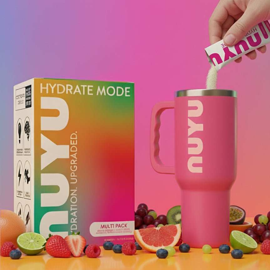 NUYU hydration electrolyte sachets UK being poured into pink tumbler with fresh fruit display