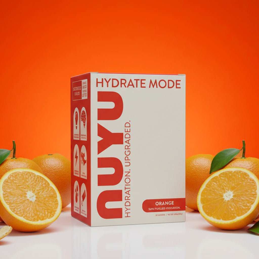 NUYU orange electrolyte sachets UK box with fresh oranges on vibrant orange backdrop