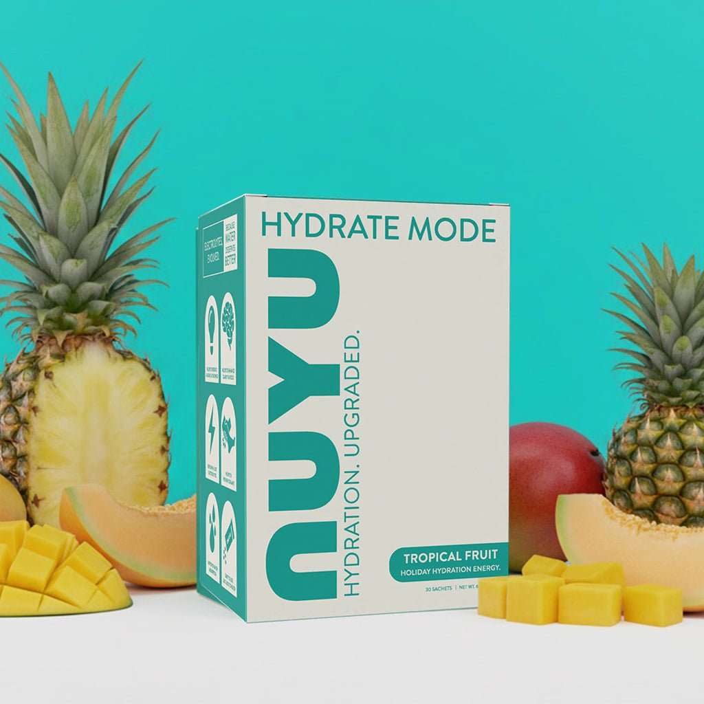 NUYU tropical fruit electrolyte sachets UK with fresh pineapple and mango on turquoise background