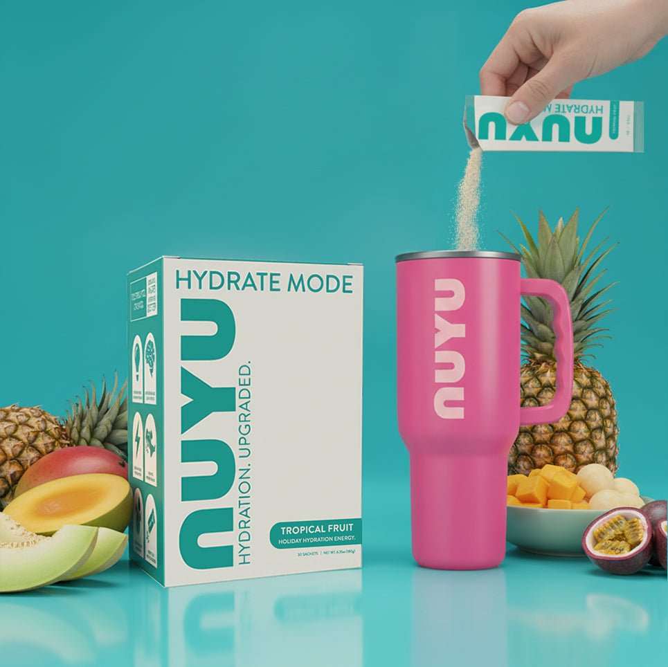 NUYU electrolyte sachets UK being poured into pink tumbler with tropical fruits on turquoise background
