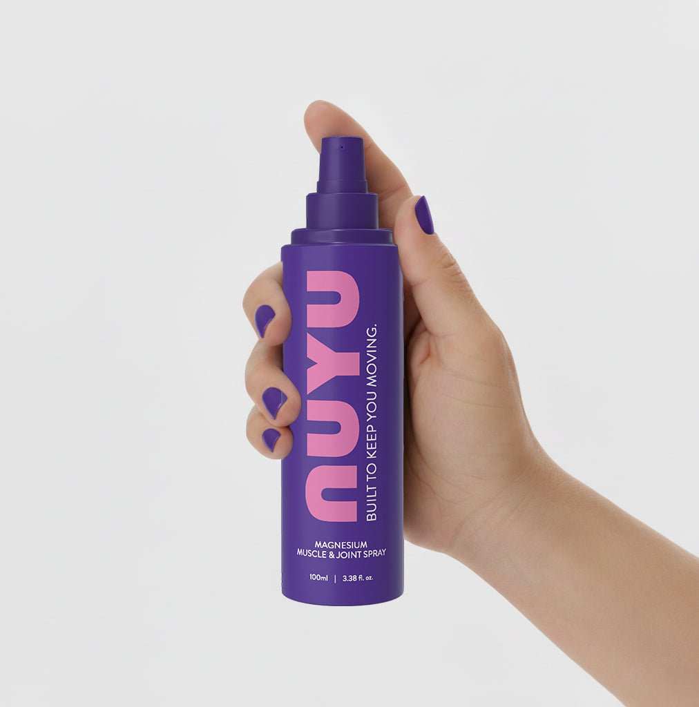 Hand holding a purple bottle of NUYU Muscle & Joint Magnesium spray for muscle recovery and joint support