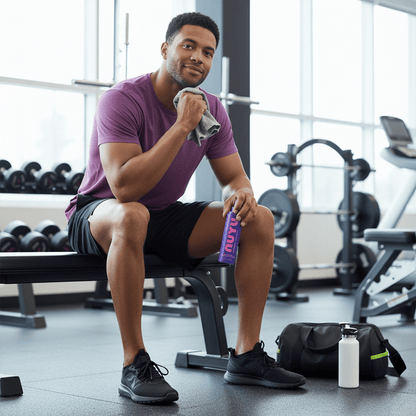 NUYU magnesium muscle recovery spray UK held by athlete in purple shirt at gym