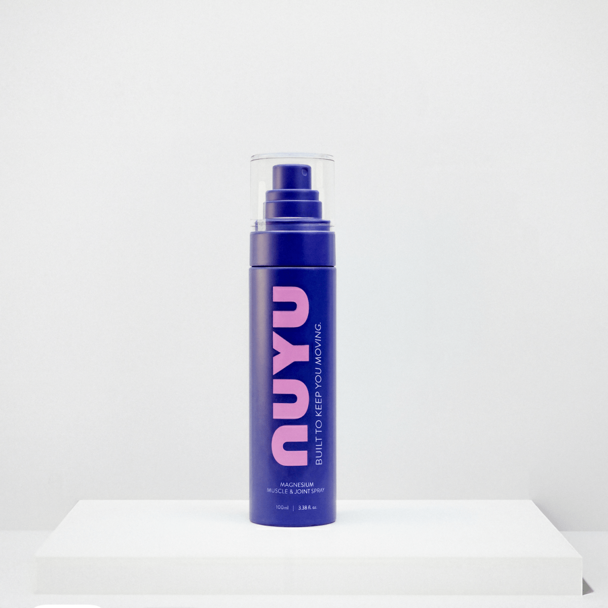 NUYU magnesium muscle recovery spray UK in purple bottle with pump dispenser on white surface
