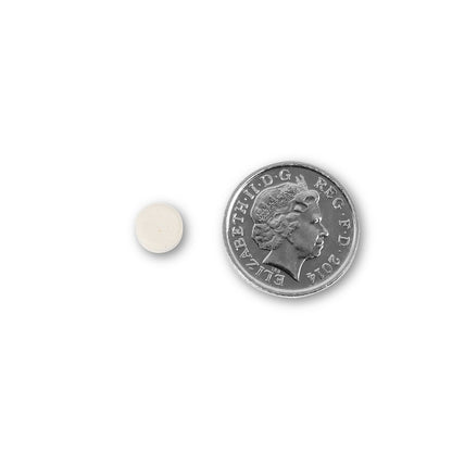 NUYU wellness supplement UK tablet next to British coin showing compact size