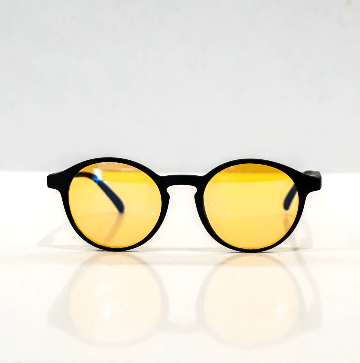 NUYU Afterlight blue light blocking glasses UK with yellow lenses and black frames on white surface