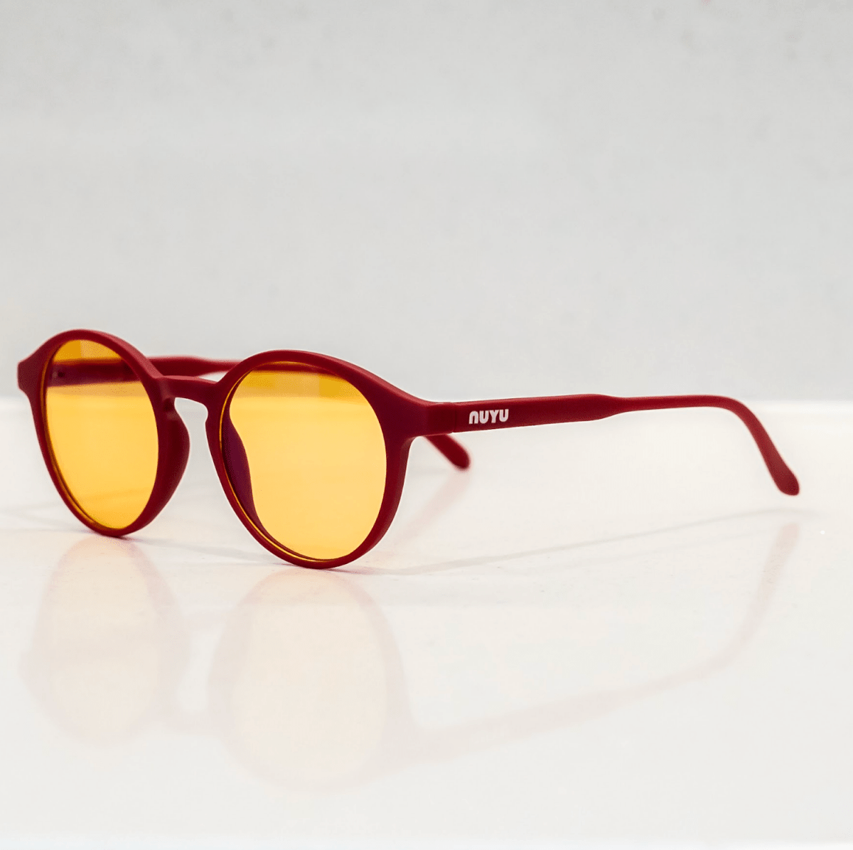 NUYU Afterlight blue light blocking glasses UK with red frames and yellow lenses on white surface