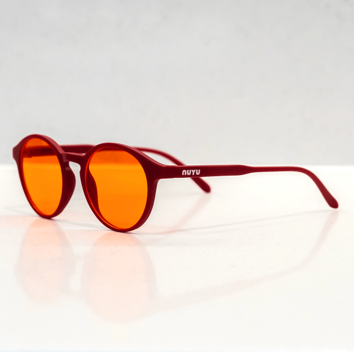 NUYU Afterlight blue light blocking glasses UK with red frames and orange lenses on white surface