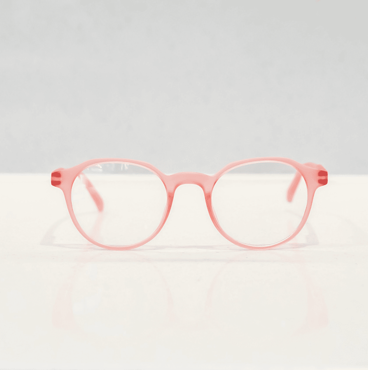 NUYU Afterlight blue light blocking glasses UK in coral pink frames on white surface