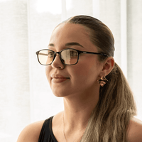 NUYU Afterlight blue light blocking glasses UK worn by woman with gold earrings by window