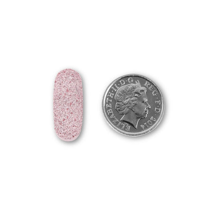 NUYU wellness supplement UK tablet shown actual size next to British coin for scale