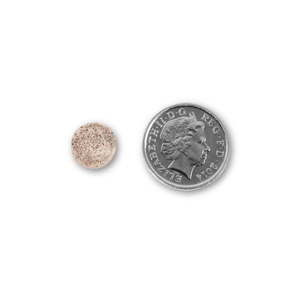NUYU biotin supplement UK tablet size comparison next to British coin on white background