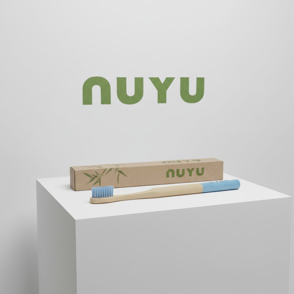 NUYU bamboo toothbrush with blue bristles and eco packaging on white display pedestal
